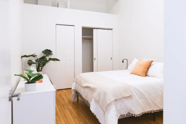 Detroit apartments for rent - image - a bedroom with white walls and a white bed with an orange pillow